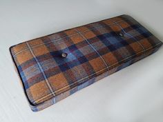 a brown and blue checkered pillow sitting on top of a white table next to a button