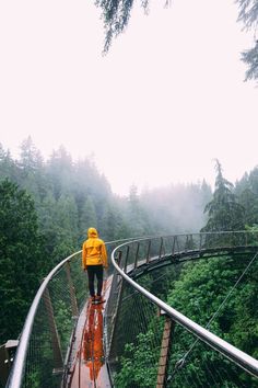 a person in yellow jacket walking across a suspension bridge