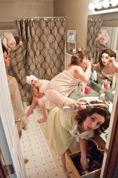 a woman in a bathrobe is looking at herself in the mirror while others are brushing her hair