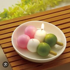 a white bowl filled with small candles on top of a wooden table