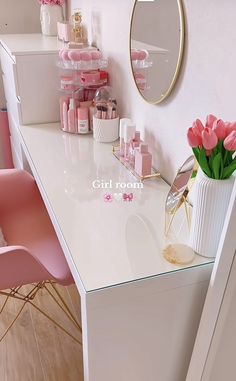 a white desk topped with pink flowers next to a mirror