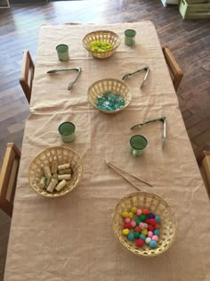 the table is set with bowls, cups and spoons on it for easter eggs