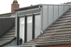 the roof of a house with two windows and some roofs covered in shinnels