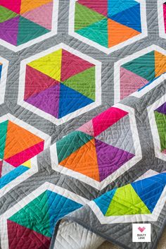 a colorful quilt is laying on the ground with it's edge folded up to show an interesting design