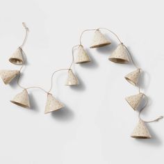 five wooden ornaments hanging from strings on a white wall with polka dotty paper and twine