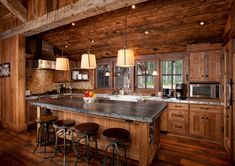 a kitchen with wooden walls and flooring has an island in the middle that is surrounded by stools