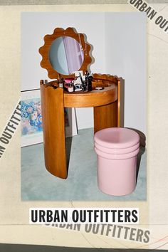 a wooden vanity table with a mirror and pink trash can