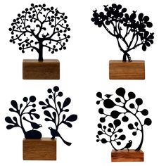 four metal tree sculptures sitting on top of wooden blocks