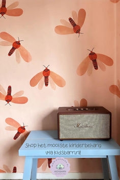 an old radio sitting on top of a blue table in front of a wall with bees