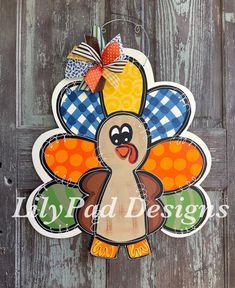 a turkey shaped door hanger on the side of a wooden door with an orange and blue checkered bow