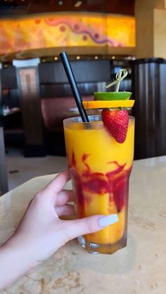 a hand holding a drink with strawberries on the rim