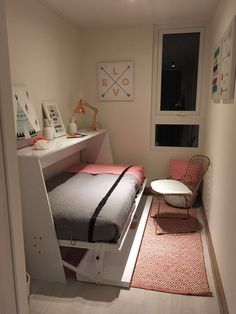 a small room with a bed, desk and chair next to a window in the corner