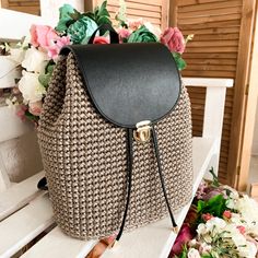 a brown and black purse sitting on top of a white bench next to some flowers