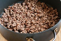 ground beef cooking in a skillet on a wooden table