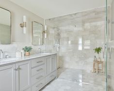 a large bathroom with marble floors and white walls, along with two sinks on both sides