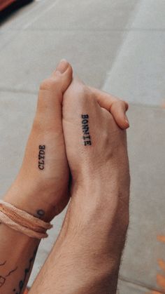 two people holding hands with tattoos on their arms