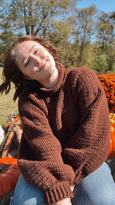 a woman sitting on the ground in front of pumpkins