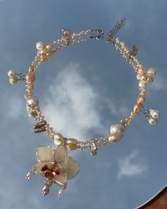 a necklace with flowers and pearls hanging from it