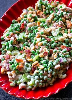 a red plate topped with peas and other food on top of a black countertop