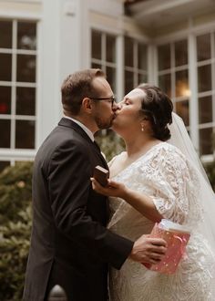 a bride and groom kissing in front of a building