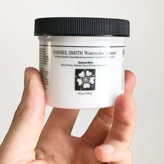 a hand holding a jar of white powder