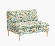 an upholstered chair with oranges and green leaves on it, against a white background