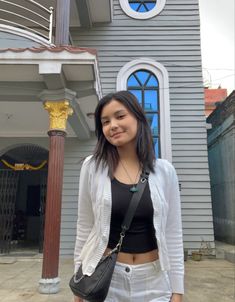 a woman standing in front of a building with a clock on it's side