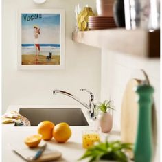 there is a sink in the kitchen with oranges on the counter next to it