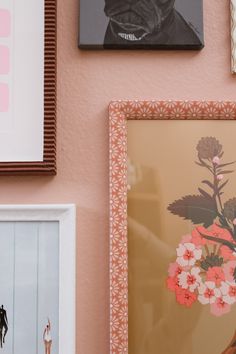 some framed pictures are hanging on the wall next to other art and decor items, including a vase with flowers in it