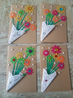 four pieces of paper with flowers in them on top of some brown paper and white doily