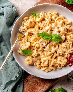 a white bowl filled with macaroni and cheese on top of a wooden cutting board