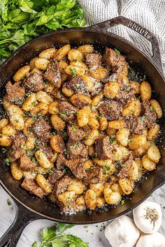 an iron skillet filled with meat and potatoes covered in parmesan sprinkles