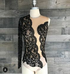 a mannequin wearing a black lace bodysuit on top of a wooden wall