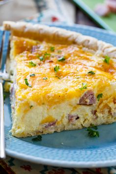 a piece of quiche on a blue plate with a fork and knife next to it