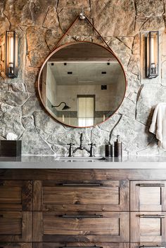 a bathroom with stone walls and a round mirror