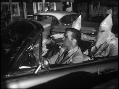 a man sitting in the driver's seat of a car with paper bags on his head