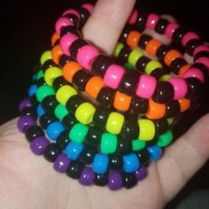 a hand is holding several multicolored bracelets