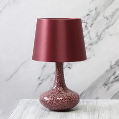 a red lamp sitting on top of a table next to a white marble wall and floor