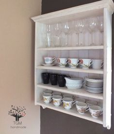 a white shelf filled with dishes and glasses