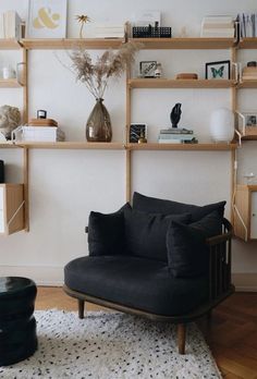 a black chair sitting on top of a rug in front of a wooden shelf filled with books