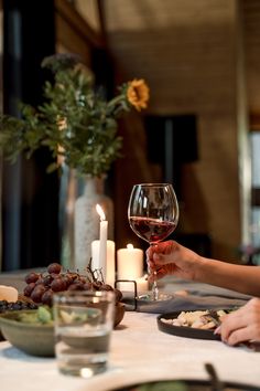 two people sitting at a table with food and wine