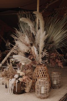 an arrangement of dried flowers and plants in wicker baskets sitting on the floor next to each other