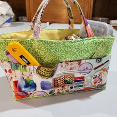 a green and white bag sitting on top of a table next to a pair of scissors