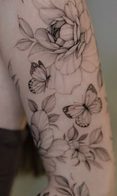 a woman's arm with flowers and butterflies tattoo on her left side ribcage