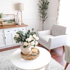 Calming hues of comforting white are applied elegantly in this farmhouse bedroom. A round coffee table is topped off with a rattan basket displaying a vase of gorgeous white flowers. A white cabinet with a polished wood top showcases different farmhouse decor including a lamp and a piece of artwork...   Image: twicebakedhome