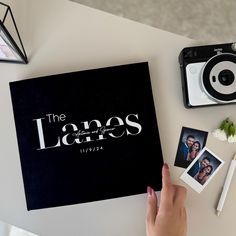 a person holding an open book on top of a table next to pictures and other items