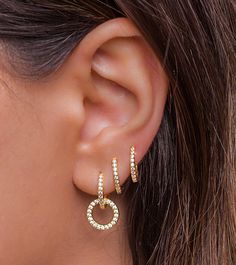 a close up of a person's ear wearing gold and white earrings with diamonds