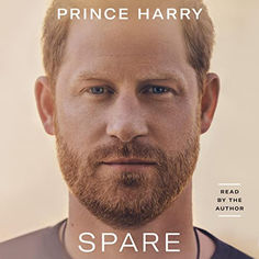 a man with a beard stares at the camera in front of an advertisement for prince harry's new book, spare