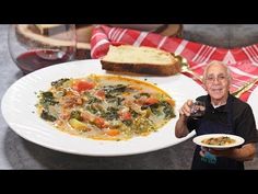 an old man is holding a plate with soup and bread on it in front of him