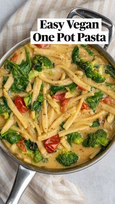 a pan filled with pasta and broccoli on top of a striped table cloth